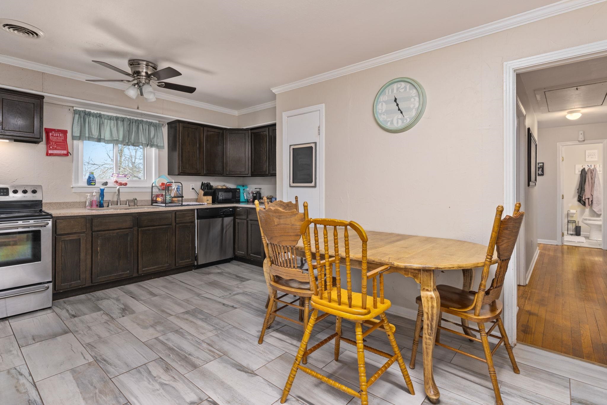 102 West 5th Street Iuka, MS 38852 - Photo 6 of 33 Kitchen featuring wood-finish flooring, dark wood cabinetry, and a stainless steel appliance suite including a range and dishwasher