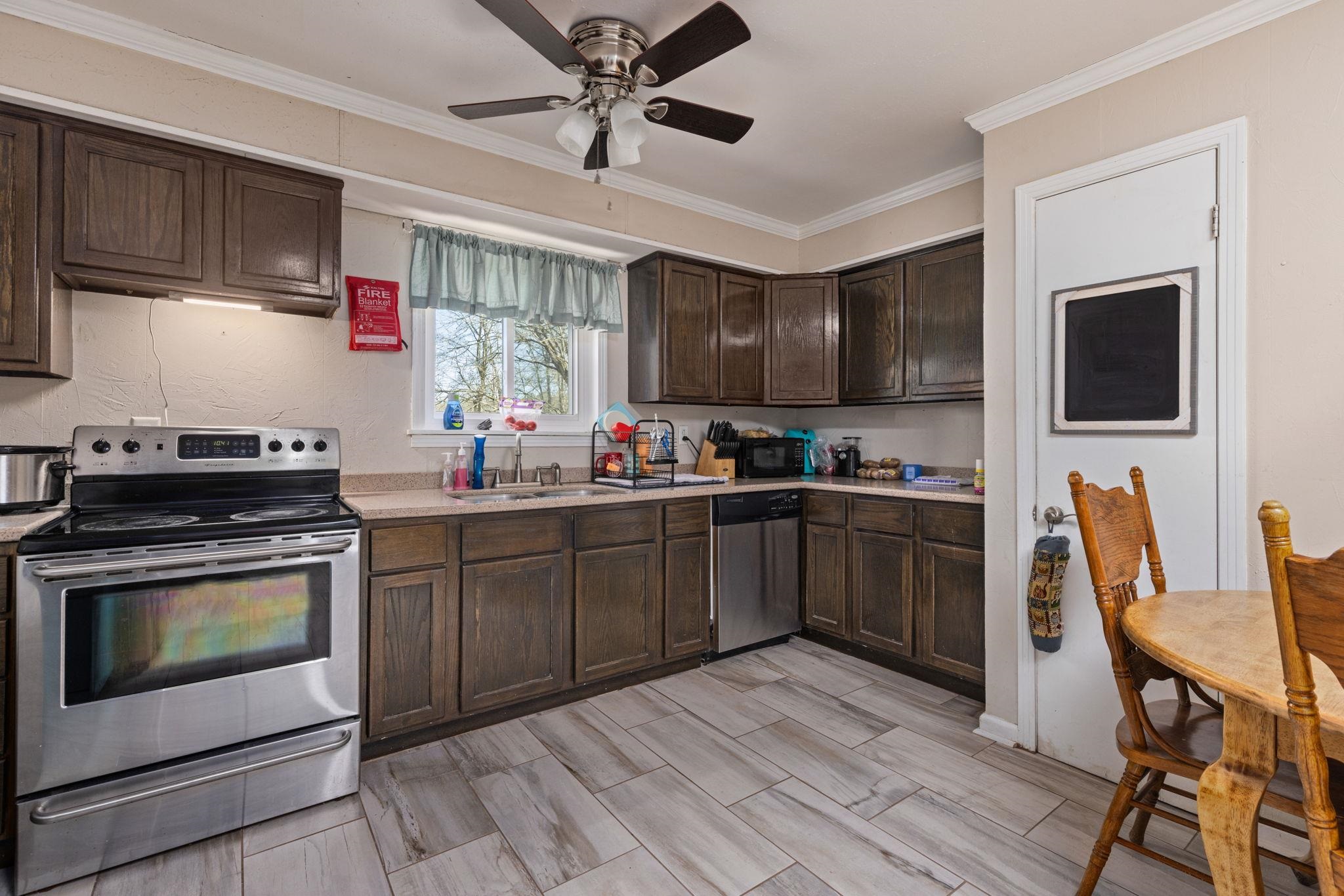 102 West 5th Street Iuka, MS 38852 - Photo 7 of 33 Kitchen featuring dark wood cabinetry, stainless steel range, stainless steel dishwasher, light-toned countertops, and wood-finish flooring