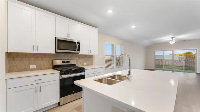 a kitchen with stainless steel appliances granite countertop a sink a stove and a refrigerator