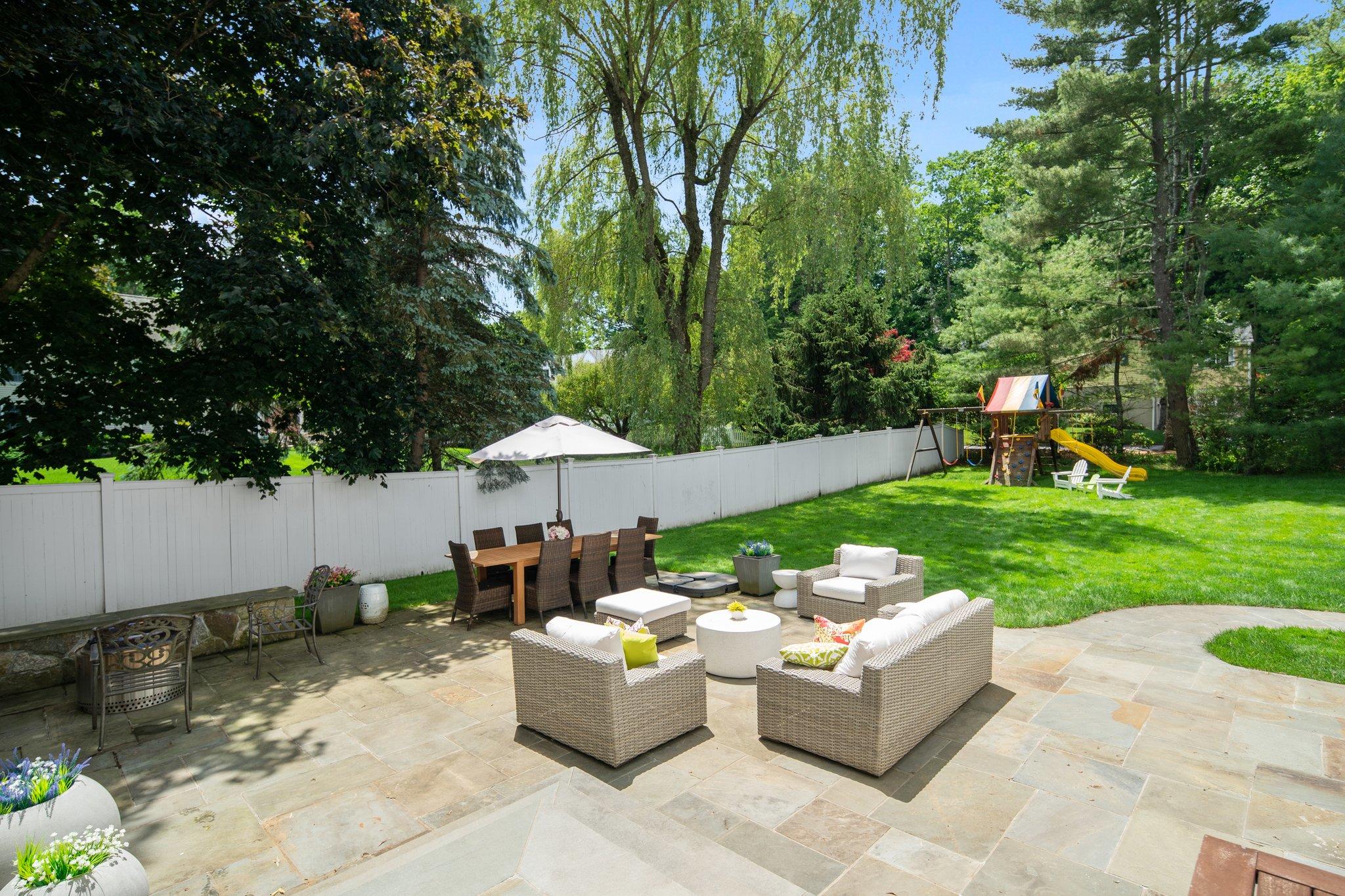 4 Parade Hill Road New Canaan, CT 06840 - Photo 42 of 50 a view of a patio with couches table and chairs under an umbrella