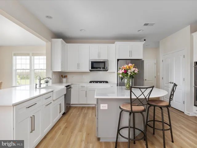 a kitchen with stainless steel appliances a stove a sink dishwasher a refrigerator white cabinets and wooden floor