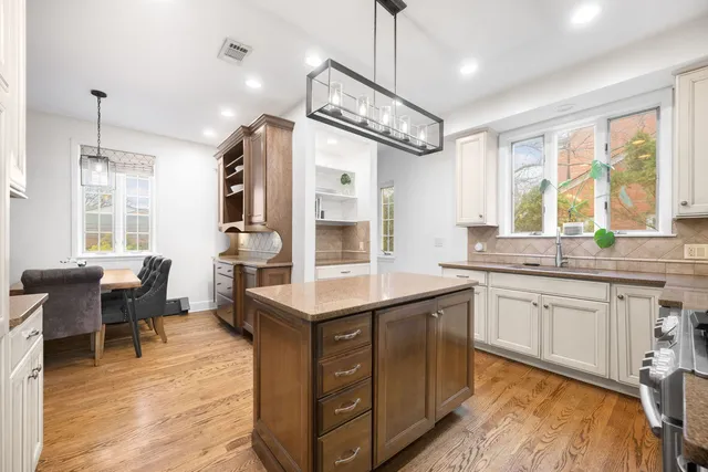 a kitchen with stainless steel appliances kitchen island granite countertop a table chairs in it and wooden floors