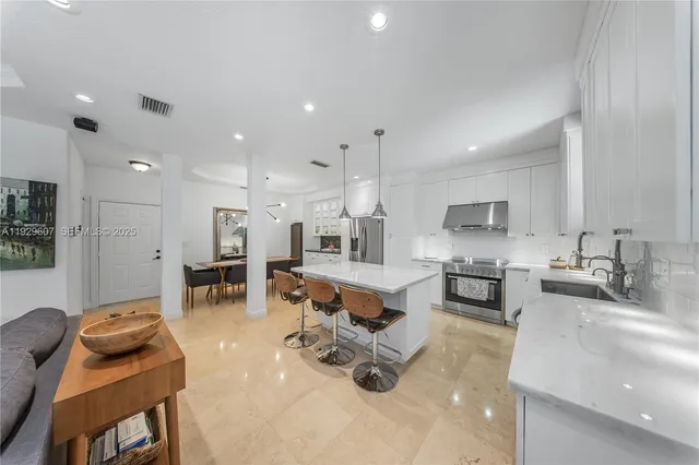 a kitchen with stainless steel appliances kitchen island granite countertop a sink and a refrigerator
