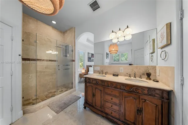 a spacious bathroom with double vanity a mirror a shower and a double vanity sink