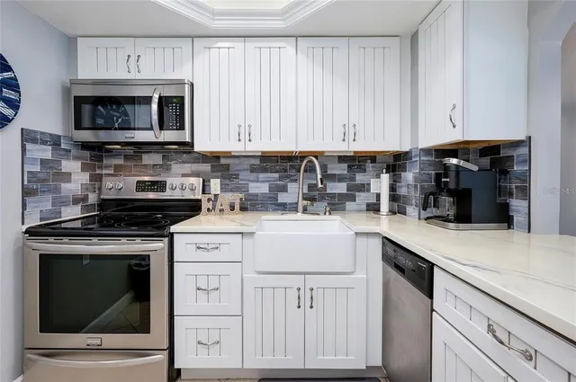 a kitchen with white cabinets and appliances