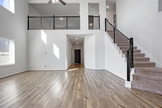 a view of empty room with wooden floor and fan