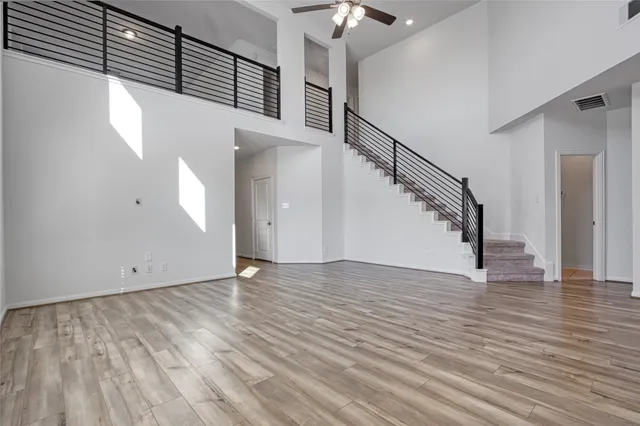 a view of an empty room with wooden floor and stairs