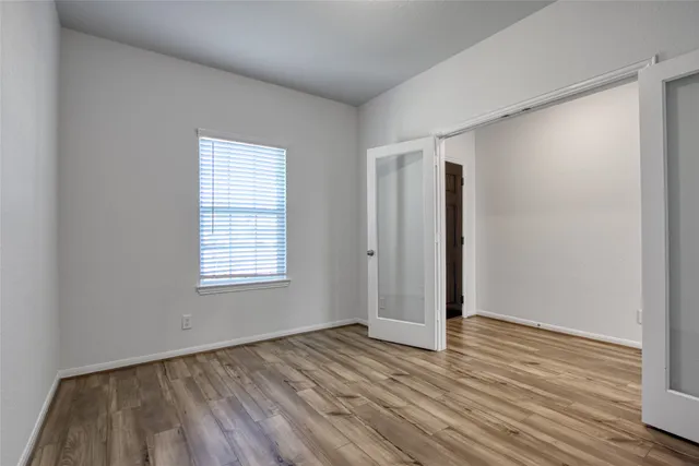 an empty room with wooden floor and windows