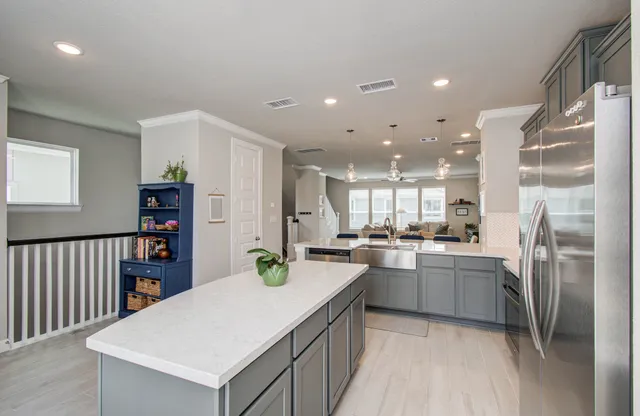 a kitchen with stainless steel appliances granite countertop a refrigerator a sink dishwasher a stove and a dining table with wooden floor