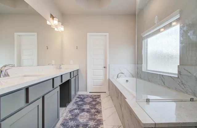 a spacious bathroom with a tub double sink and mirror