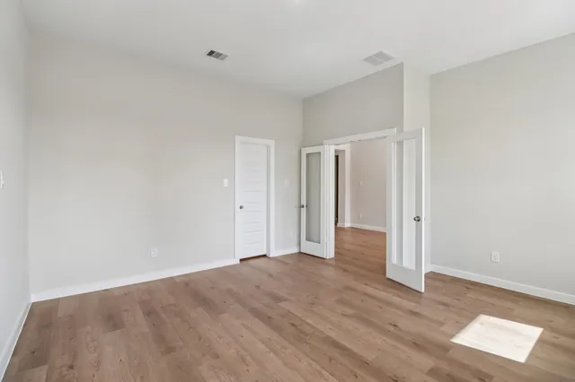 a view of an empty room with wooden floor and a window
