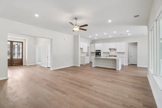 a view of an empty room with kitchen appliances and a ceiling fan