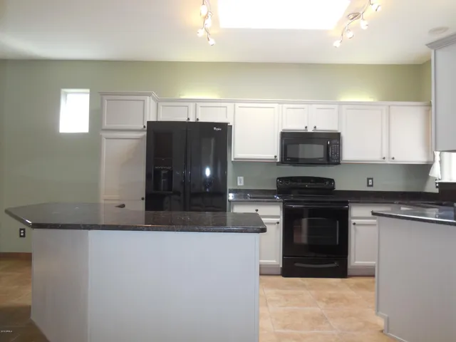 a kitchen with stainless steel appliances granite countertop a refrigerator and a stove top oven