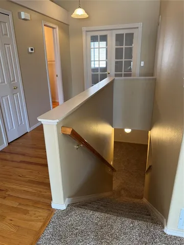 a view of a hallway to an empty room with wooden floor and windows