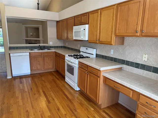 a kitchen with wooden floors and white appliances