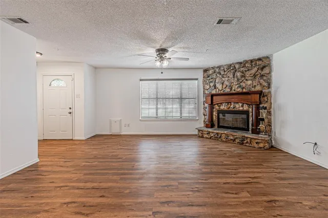 an empty room with windows fireplace and wooden floor