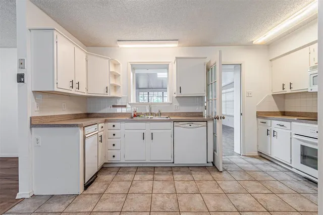 a kitchen with granite countertop white cabinets and appliances