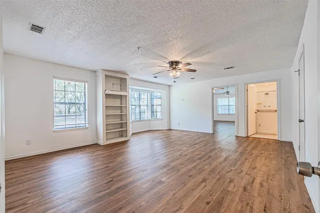 a view of an empty room with a window and wooden floor