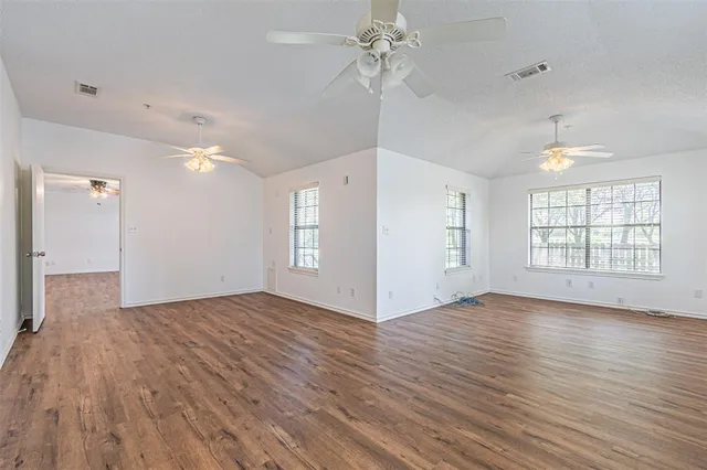 a view of an empty room with a window and wooden floor