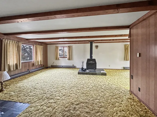 a view of an empty room with window and chandelier fan