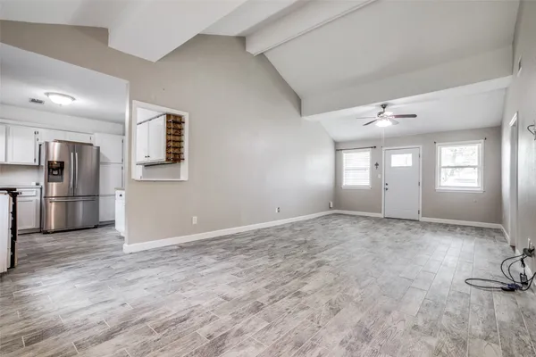 a view of an empty room and a kitchen