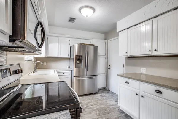 a kitchen with kitchen island a counter top space a sink stainless steel appliances and cabinets