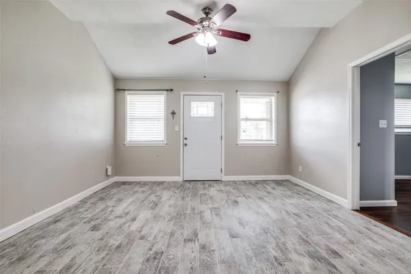 a view of an empty room with window and wooden floor