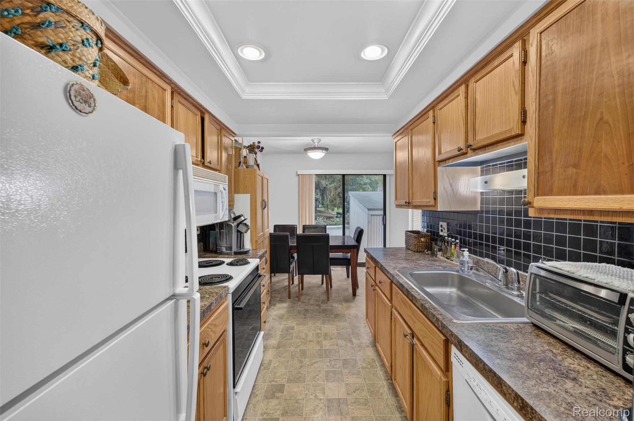 1439 Oakbrook E Drive Rochester, MI 48307 - Photo 15 of 68 Galley kitchen with wood cabinetry, laminate countertops, and a black tile backsplash