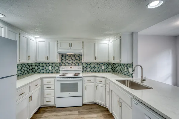 a kitchen with white cabinets and white appliances