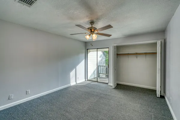 an empty room with chandelier fan and windows