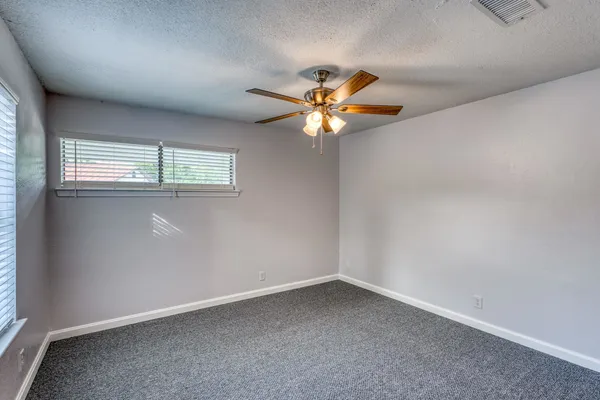 an empty room with windows and chandelier fan