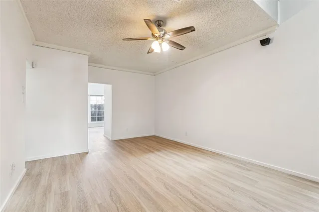 an empty room with wooden floor and ceiling fan