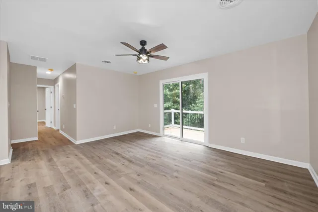 a view of an empty room with a window and wooden floor