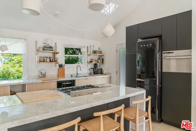 a living room with stainless steel appliances kitchen island granite countertop furniture and a large window