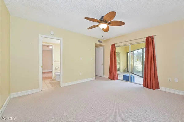 an empty room with chandelier fan and windows