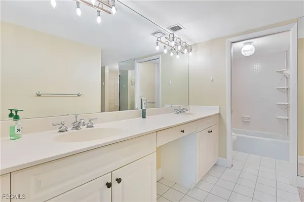 a bathroom with a double vanity sink mirror and bathtub