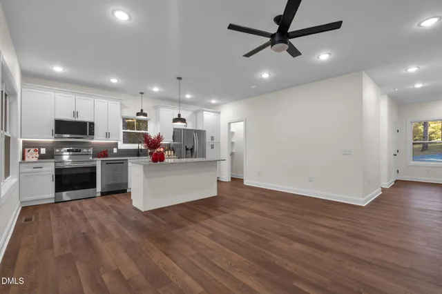 a kitchen with stainless steel appliances granite countertop a refrigerator oven a sink dishwasher and a stove with wooden floor