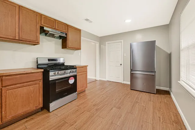 a kitchen with stainless steel appliances wooden floor sink and wooden cabinets