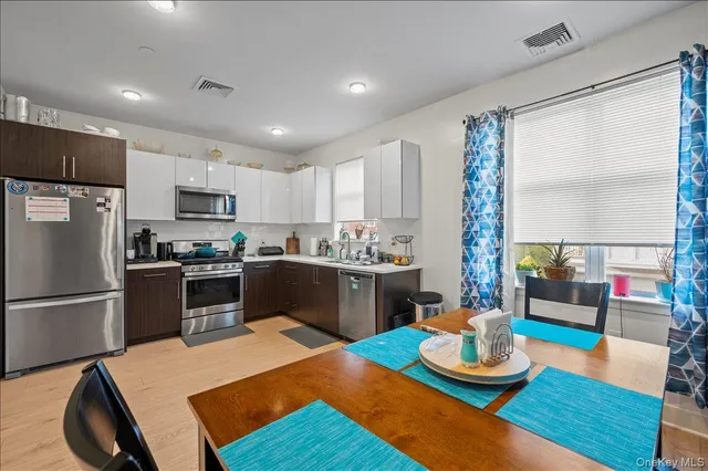 a kitchen with a refrigerator coffee maker on table and chairs