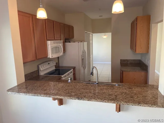 a kitchen with kitchen island granite countertop a sink a stove and refrigerator