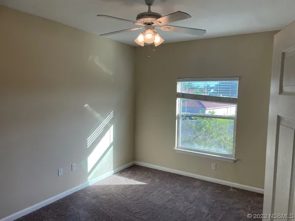 a view of an empty room with window and chandelier fan