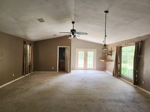 a view of empty room with windows and ceiling fan