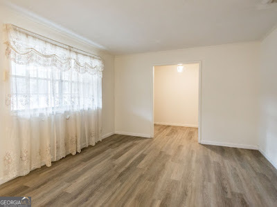 5209 Highway 32 Patterson, GA 31557 - Photo 17 of 45 an empty room with wooden floor and windows with curtains