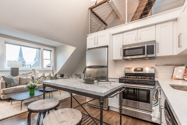 a kitchen with stainless steel appliances a stove a microwave a dining table and chairs