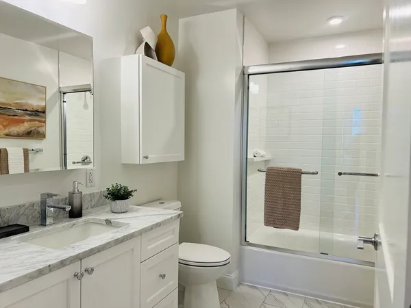 a bathroom with a granite countertop sink toilet and shower