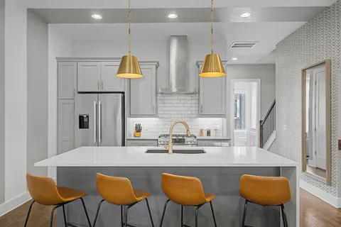 a kitchen with stainless steel appliances a dining table chairs and a sink