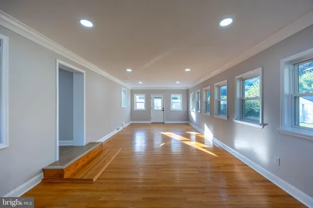 a view of an empty room with wooden floor fireplace and a window