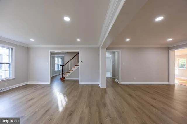 an empty room with wooden floor and natural light