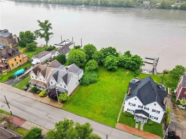 an aerial view of residential houses with outdoor space and trees