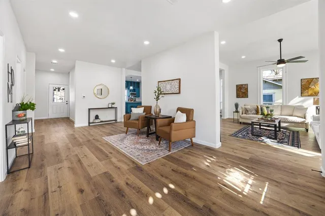 a living room with furniture and a dining table with wooden floor